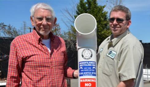 Wes Batten and Dave Milby hold a recycling container.